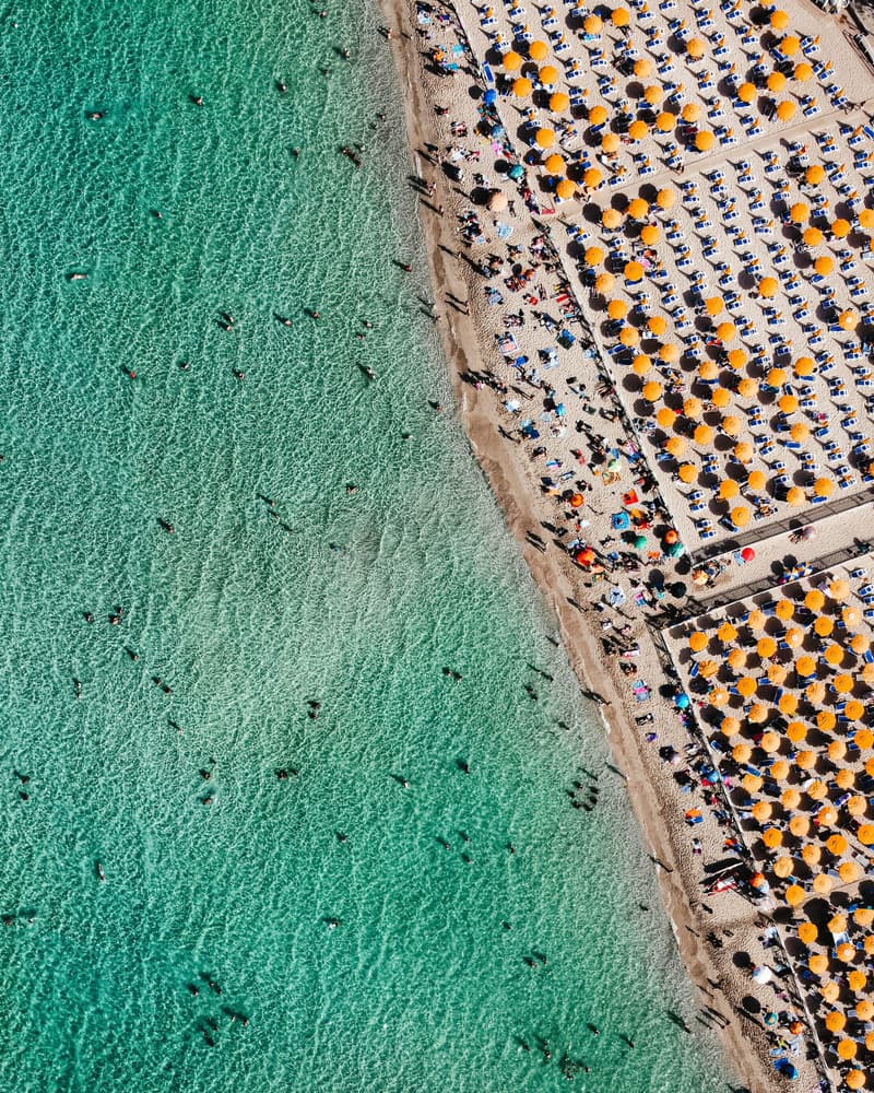 Vista aerea della spiaggia di Mondello, a Palermo: file ordinate di ombrelloni arancioni accanto al mare turchese